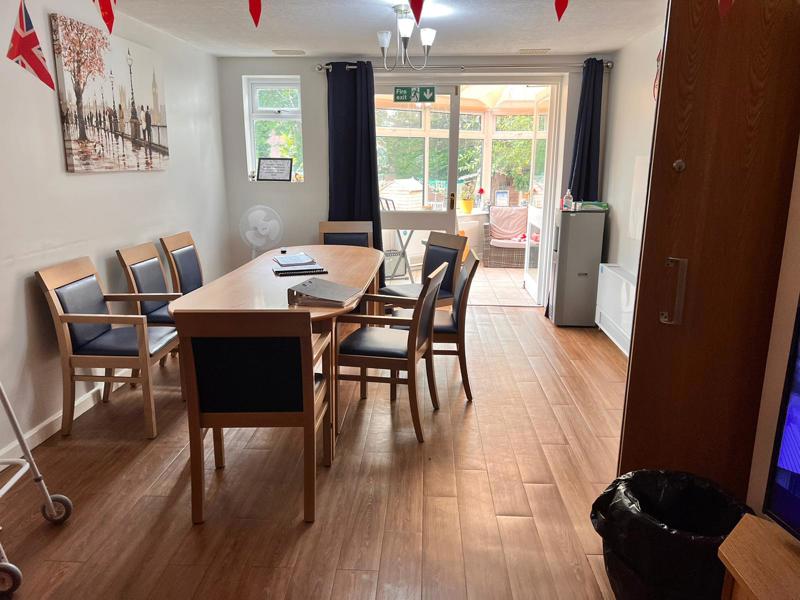 Dining room at Chesterwood with a wooden table, chairs and a conservatory beyond