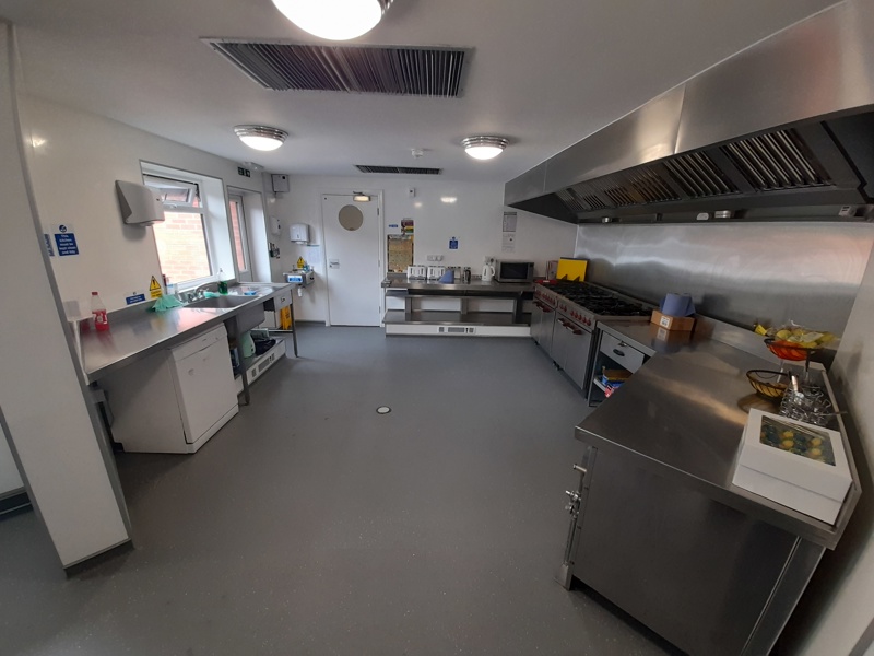 Commercial catering kitchen at Boston House with stainless steel surfaces, a range cooker and extractor hood