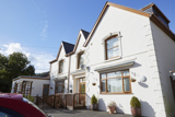 Side view of Isfryn, a white rendered house with gabled roofs and arched sash windows