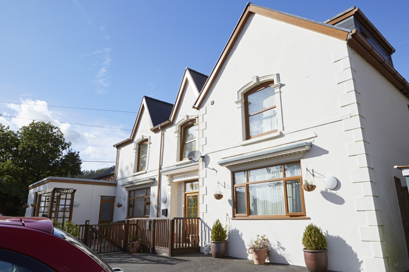 Side view of Isfryn, a white rendered house with gabled roofs and arched sash windows