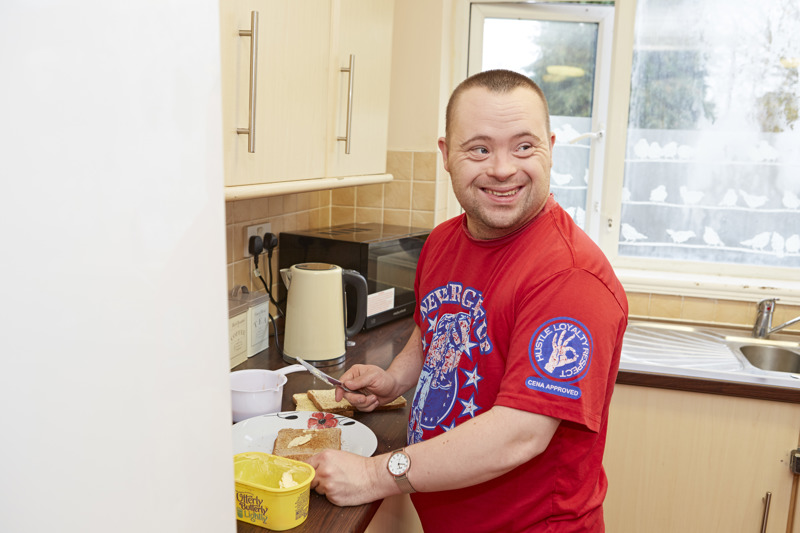 A resident buttering toast in the kitchen at Blackwells