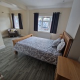 Spacious bedroom at Birchwood House with an oak double bed, armchair and two curtained windows