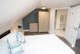Loft bedroom at Willow Lodge with a double bed, cream wardrobe and an ensuite wet room through the door