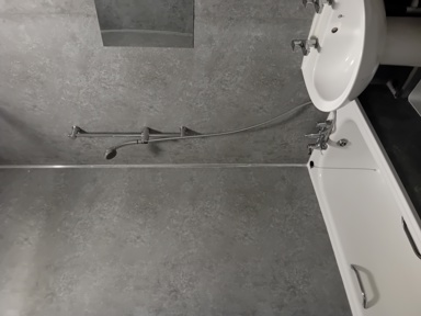 Bathroom at Eynesbury House with a bath, basin and a wall-mounted shower over grey tiling