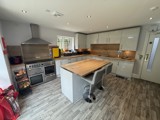 Kitchen at Manor Farm with grey units, wooden worktops, a range cooker and an island with stools