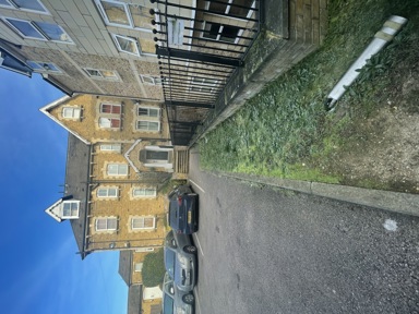 Front exterior of Kemble House, a yellow-brick Victorian building with cars parked on the drive