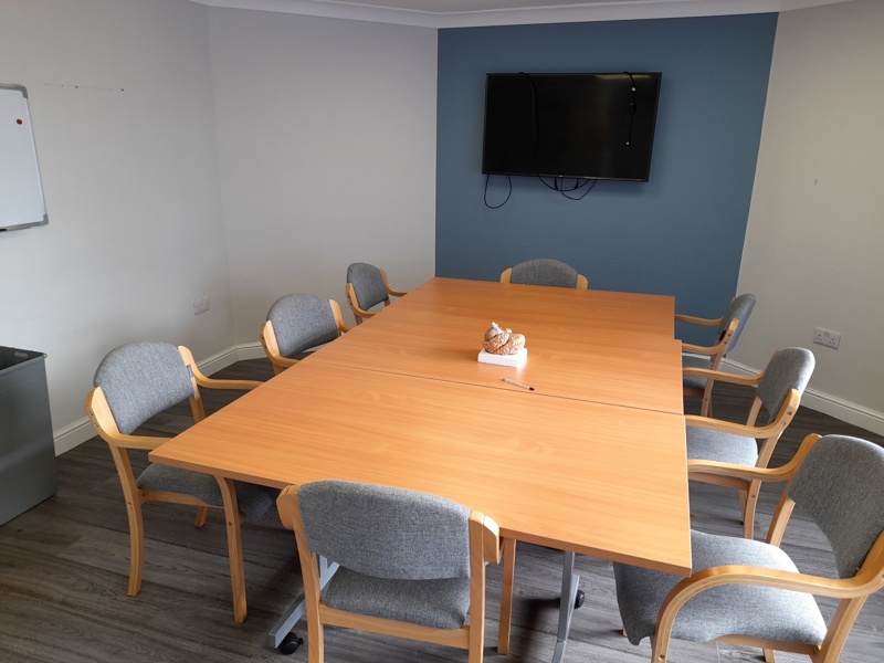 Meeting room at Boston House with a large wooden table, grey chairs and an anatomical brain model