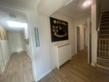 Hallway at Rosewood with a Welcome to Rosewood sign, a staircase and a wooden floor