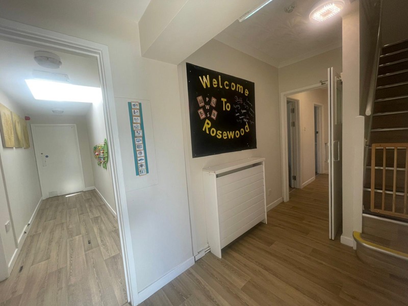 Hallway at Rosewood with a Welcome to Rosewood sign, a staircase and a wooden floor