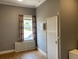 Bedroom at Cranwell Court with a curtained sash window, radiator cover and first aid cabinet