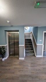 Lift and staircase at Cedar House with handrails in a blue-painted hallway