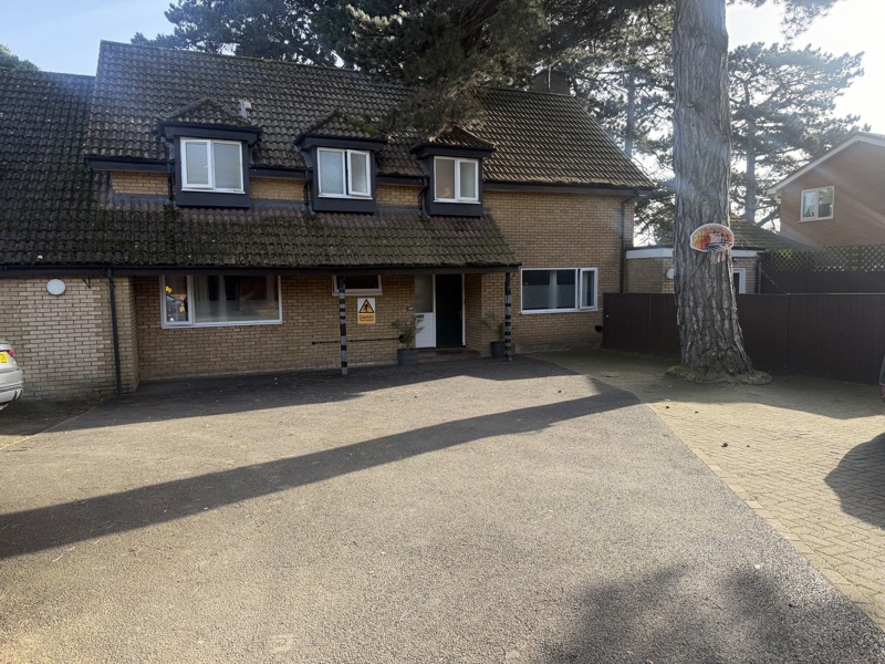 Front exterior of Pinetrees, a yellow-brick house with dormer windows and a gravel driveway