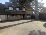 Front exterior of Pinetrees, a yellow-brick house with dormer windows and a gravel driveway