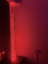 Sensory bubble tube glowing red in the corner of a sensory room at Pinetrees