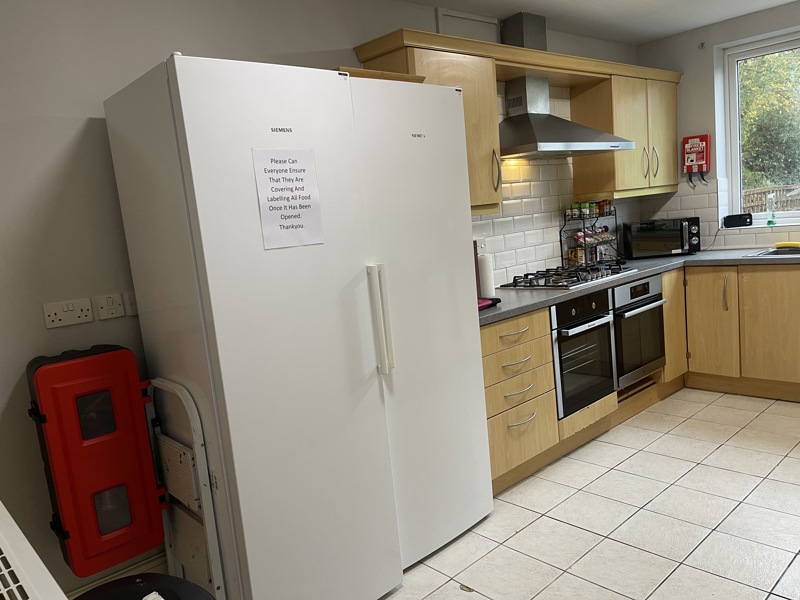 Kitchen at Glanmore with wooden units, a gas hob, double oven, two tall fridge freezers and tiled floor