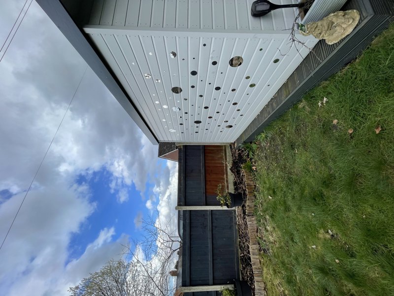 Covered decking and seating area in the rear garden at Glanmore, with a pergola canopy and lawn