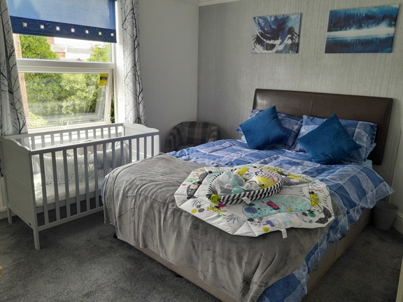 Family bedroom at Victoria Villas with a double bed, a baby cot by the window and a play mat