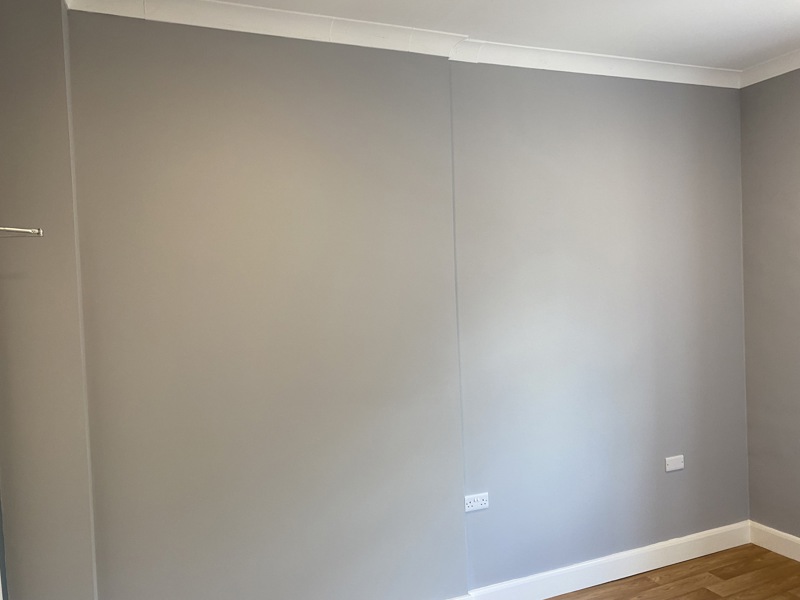Empty room at Cranwell Court with grey walls, a curtain rail and a wood-effect floor