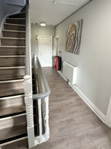 Light coloured hallway with staircase and artwork on the walls.