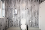 Wet room at Brynawel with grey wood-effect panelling, an electric shower and a toilet