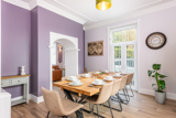 Dining room at Brynawel with a wooden table set for a meal, beige chairs and lilac walls