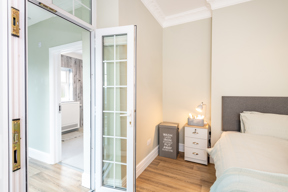 Bedroom at Brynawel with a single bed, a bedside table with lamp and a glazed door to an en-suite