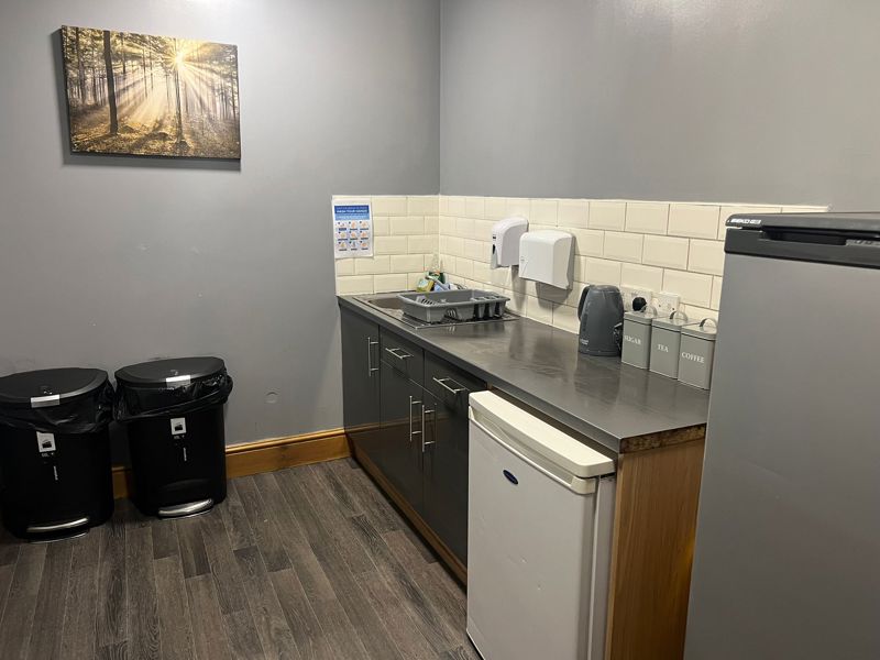 Kitchen area at Byron Lodge with worktop, sink, kettle and tea, coffee and sugar canisters