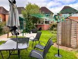 Rear garden at Chesterwood with a paved patio, parasol table, lawn and timber shed