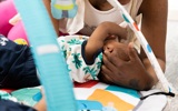 Parent playing with a baby on a colourful play mat under a baby gym at Crown House family assessment centre