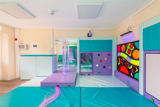 Sensory play room with jade coloured matts, purple elements and a brightly coloured and patterned wall.