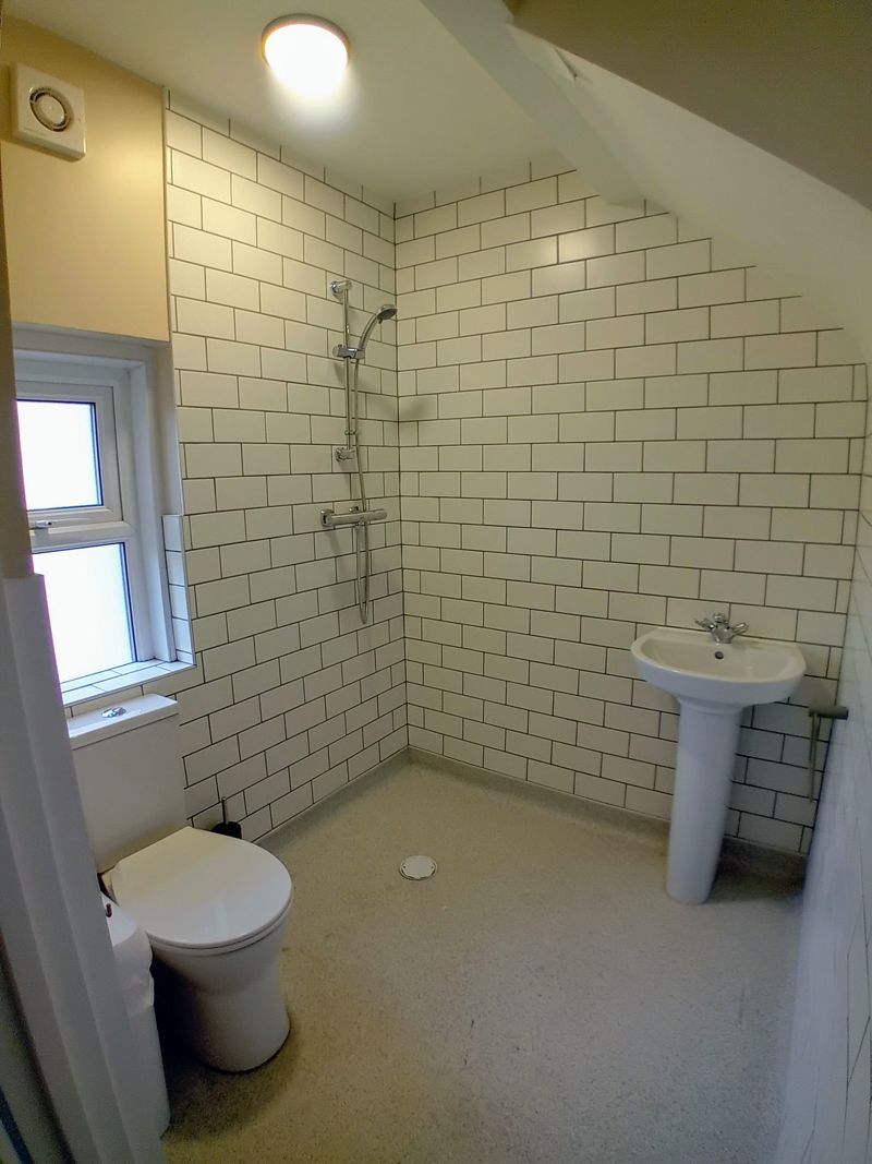 Wet room at Bayview Lodge with a walk-in shower, white metro tiling, toilet and pedestal basin