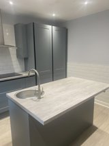 Kitchen at Maple Leaf Lodge with grey units, tall larder cupboards and a central island