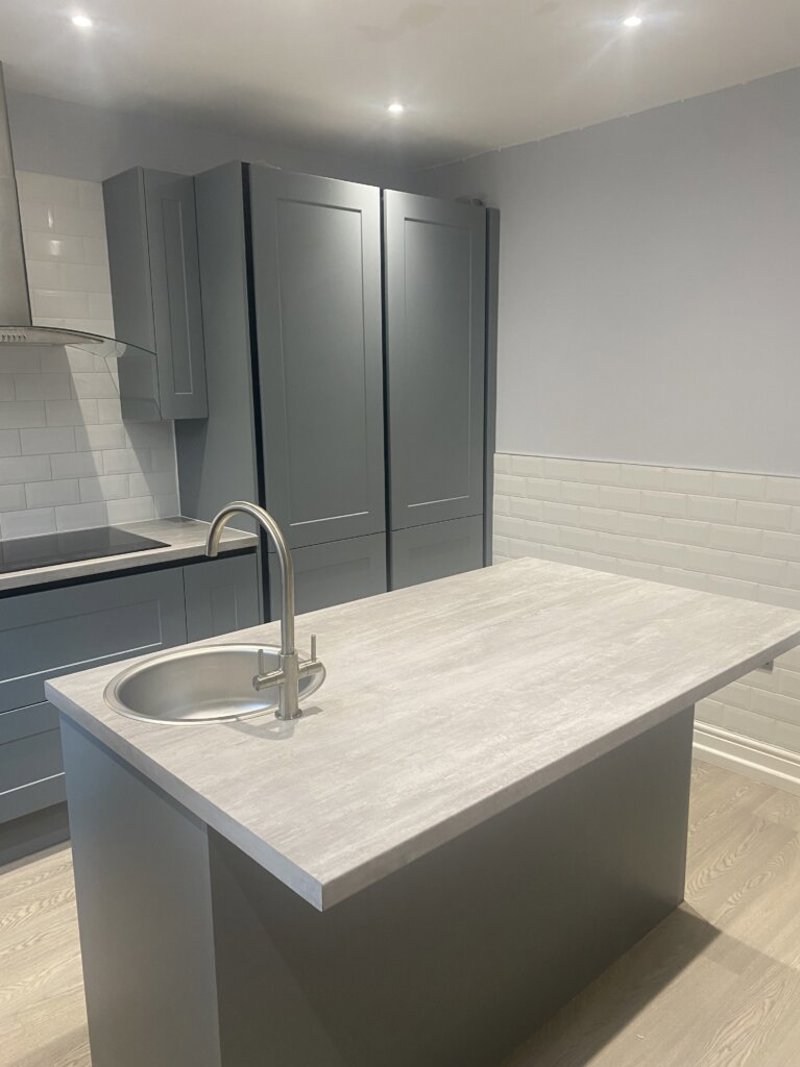 Kitchen at Maple Leaf Lodge with grey units, tall larder cupboards and a central island