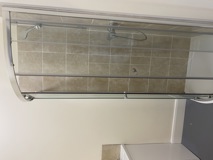 Quadrant shower enclosure with beige tiling and sliding glass doors at Cranwell Court