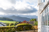 View of the Brecon Beacons from Brynawel, with green fields and a bay window in the foreground