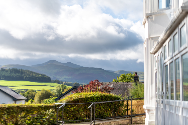 View of the Brecon Beacons from Brynawel, with green fields and a bay window in the foreground