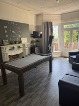 Games room at Manor Lodge with a pool table, boxing bag, TV and a large wall clock