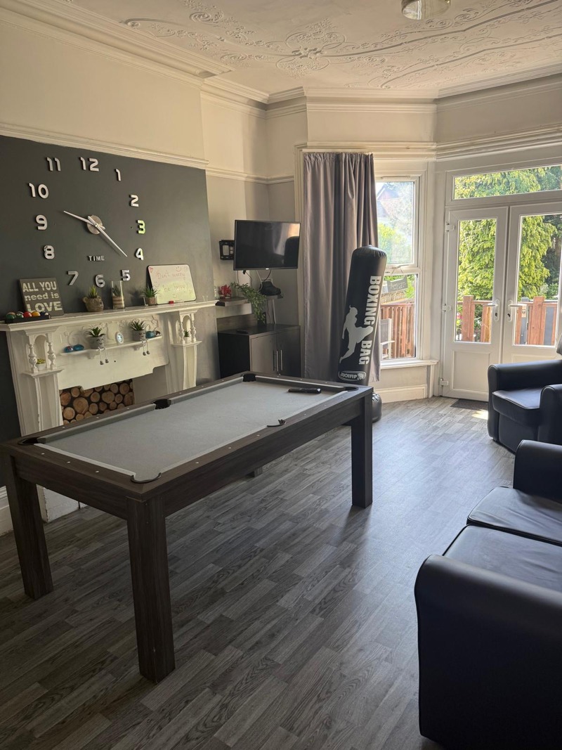 Games room at Manor Lodge with a pool table, boxing bag, TV and a large wall clock