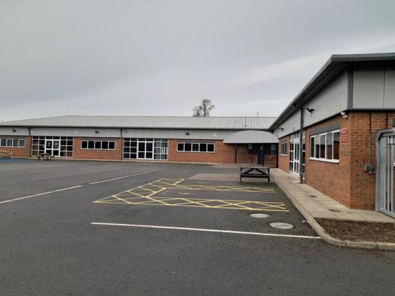 Single-storey brick and grey-clad exterior of South Park Enterprise College with a car park and picnic bench