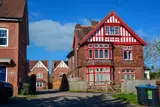 Front exterior of Red House, a red-brick mock-Tudor building with red window frames and a gabled roof
