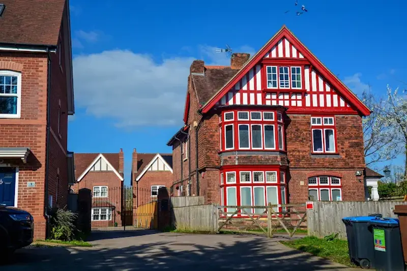 Front exterior of Red House, a red-brick mock-Tudor building with red window frames and a gabled roof