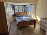 Bedroom at Chesterwood with a wooden double bed, bay window and chest of drawers