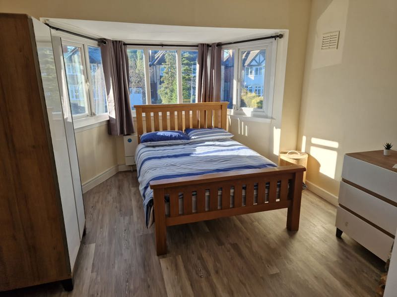 Bedroom at Chesterwood with a wooden double bed, bay window and chest of drawers