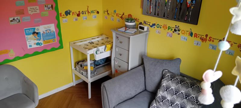 Bright nursery at Clairmont with a baby changing table, alphabet wall and safer sleep information board