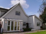 Front exterior of Rosewood, a white pebbledashed house with French doors and a garden
