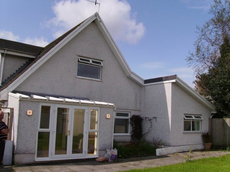 Front exterior of Rosewood, a white pebbledashed house with French doors and a garden