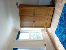 Bedroom at Eynesbury House with a large oak chest of drawers, a window and a bright blue rug
