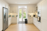 Kitchen at Brynawel with cream shaker units, an American-style fridge and French doors to the garden