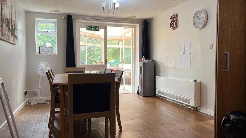 Dining area at Chesterwood with a wooden table, water cooler and doors to the conservatory