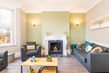 Lounge at Bayview Lodge with grey sofas, a white ornate fireplace and a sage-green feature wall